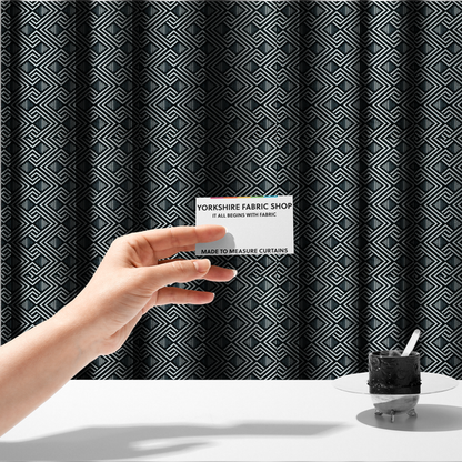 The fabric used to create these made-to-measure curtains is a geometric pattern featuring a repeating labyrinthine or Greek key-inspired design. The fabric has a high-contrast black and white colour scheme, with white interlocking lines forming diamond shapes and diagonal pathways against a deep black background.