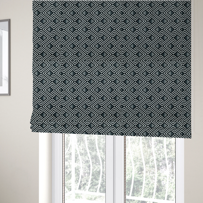 The fabric used to create these Roman blinds is a geometric pattern featuring a repeating labyrinthine or Greek key-inspired design. The fabric has a high-contrast black and white colour scheme, with white interlocking lines forming diamond shapes and diagonal pathways against a deep black background.