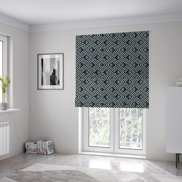 The fabric used to create these Roman blinds is a geometric pattern featuring a repeating labyrinthine or Greek key-inspired design. The fabric has a high-contrast black and white colour scheme, with white interlocking lines forming diamond shapes and diagonal pathways against a deep black background.