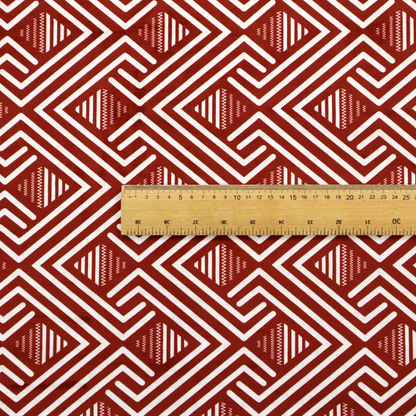 A bold geometric pattern featuring an interlocking labyrinth or fretwork design. The fabric is set in a striking terracotta red and cream colour palette, where crisp white lines weave together to form diagonal chains and diamond shapes against a rich, earthy red background.