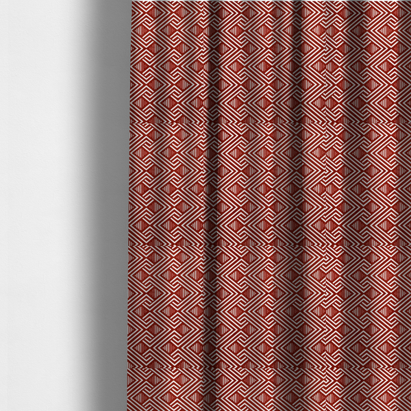 The fabric used to create these made-to-measure curtains is a bold geometric pattern featuring an interlocking labyrinth or fretwork design. The fabric is set in a striking terracotta red and cream colour palette, where crisp white lines weave together to form diagonal chains and diamond shapes against a rich, earthy red background.
