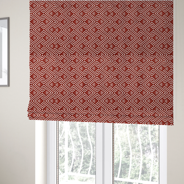 The fabric used to create these Roman blinds is a bold geometric pattern featuring an interlocking labyrinth or fretwork design. The fabric is set in a striking terracotta red and cream colour palette, where crisp white lines weave together to form diagonal chains and diamond shapes against a rich, earthy red background.