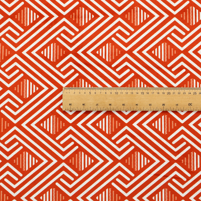 A vibrant geometric pattern with a repeating labyrinth or fretwork motif. The fabric is designed in a high-energy orange and white colour palette, with crisp white interlocking lines creating diagonal paths and diamond shapes against a bright, warm orange background.