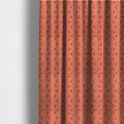 The fabric used to create these made-to-measure curtains is a vibrant geometric pattern with a repeating labyrinth or fretwork motif. The fabric is designed in a high-energy orange and white colour palette, with crisp white interlocking lines creating diagonal paths and diamond shapes against a bright, warm orange background.