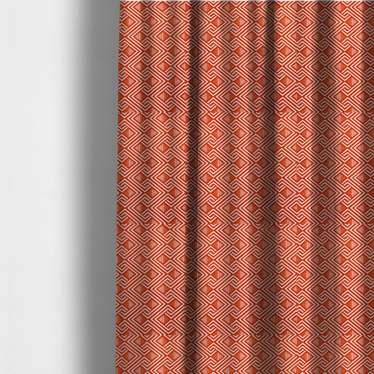 The fabric used to create these made-to-measure curtains is a vibrant geometric pattern with a repeating labyrinth or fretwork motif. The fabric is designed in a high-energy orange and white colour palette, with crisp white interlocking lines creating diagonal paths and diamond shapes against a bright, warm orange background.