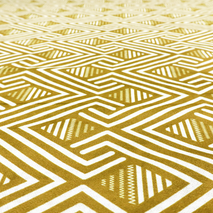 A dynamic geometric pattern with a repeating labyrinth or fretwork motif. The fabric showcases a sophisticated mustard yellow and white colour palette, with crisp white interlocking lines creating diagonal chains and diamond shapes against a warm, golden-yellow background.