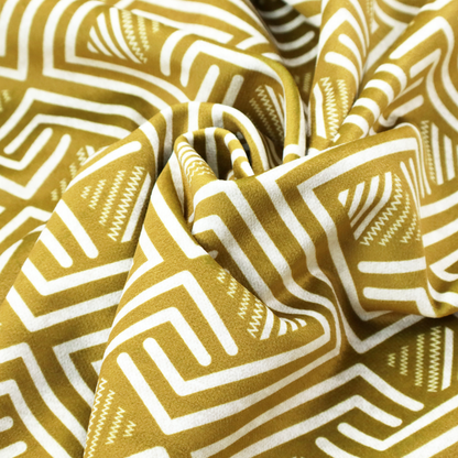 A dynamic geometric pattern with a repeating labyrinth or fretwork motif. The fabric showcases a sophisticated mustard yellow and white colour palette, with crisp white interlocking lines creating diagonal chains and diamond shapes against a warm, golden-yellow background.