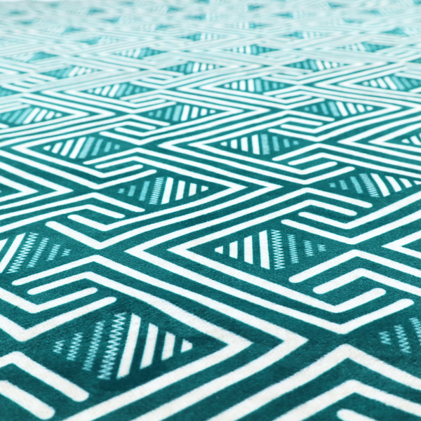 A striking geometric pattern featuring an interlocking labyrinth or fretwork motif. The fabric is set in a refreshing teal and white colour palette, with crisp white lines weaving together to form diagonal chains and diamond shapes against a rich, deep sea-green background.