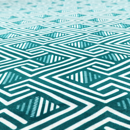 A striking geometric pattern featuring an interlocking labyrinth or fretwork motif. The fabric is set in a refreshing teal and white colour palette, with crisp white lines weaving together to form diagonal chains and diamond shapes against a rich, deep sea-green background.