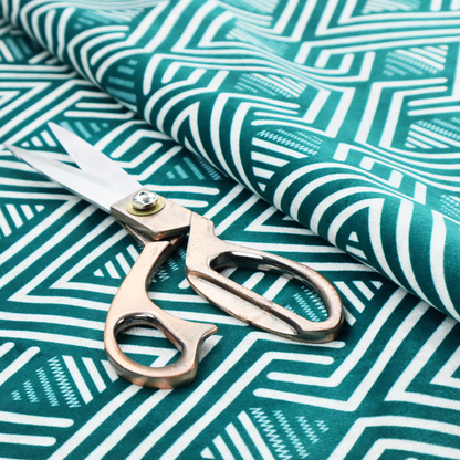 A striking geometric pattern featuring an interlocking labyrinth or fretwork motif. The fabric is set in a refreshing teal and white colour palette, with crisp white lines weaving together to form diagonal chains and diamond shapes against a rich, deep sea-green background.