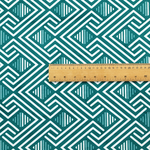 A striking geometric pattern featuring an interlocking labyrinth or fretwork motif. The fabric is set in a refreshing teal and white colour palette, with crisp white lines weaving together to form diagonal chains and diamond shapes against a rich, deep sea-green background.