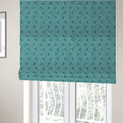 The fabric used to create these Roman blinds is a striking geometric pattern featuring an interlocking labyrinth or fretwork motif. The fabric is set in a refreshing teal and white colour palette, with crisp white lines weaving together to form diagonal chains and diamond shapes against a rich, deep sea-green background.