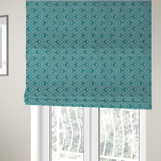 The fabric used to create these Roman blinds is a striking geometric pattern featuring an interlocking labyrinth or fretwork motif. The fabric is set in a refreshing teal and white colour palette, with crisp white lines weaving together to form diagonal chains and diamond shapes against a rich, deep sea-green background.