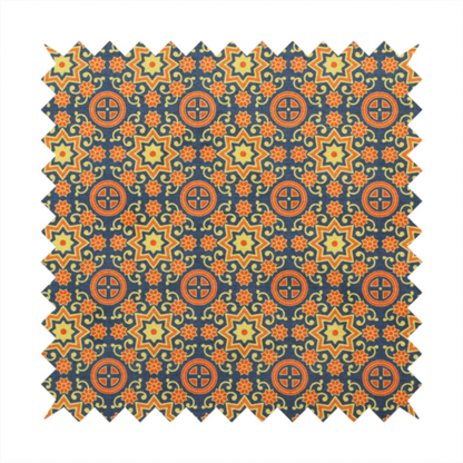 A dense, symmetrical textile pattern featuring a repeating grid of pale yellow eight-pointed stars and orange circular medallions. The motifs are interconnected by delicate orange scrolling vines and tiny floral accents, set against a deep navy blue background. The colour palette consists of mustard yellow, burnt orange, and indigo.