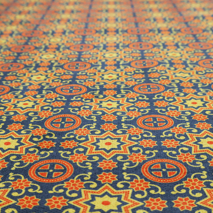 A dense, symmetrical textile pattern featuring a repeating grid of pale yellow eight-pointed stars and orange circular medallions. The motifs are interconnected by delicate orange scrolling vines and tiny floral accents, set against a deep navy blue background. The colour palette consists of mustard yellow, burnt orange, and indigo.