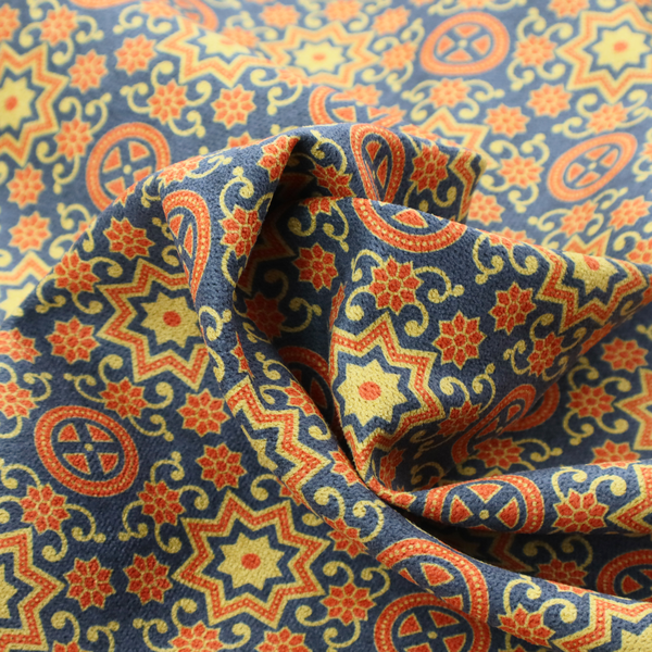 A dense, symmetrical textile pattern featuring a repeating grid of pale yellow eight-pointed stars and orange circular medallions. The motifs are interconnected by delicate orange scrolling vines and tiny floral accents, set against a deep navy blue background. The colour palette consists of mustard yellow, burnt orange, and indigo.