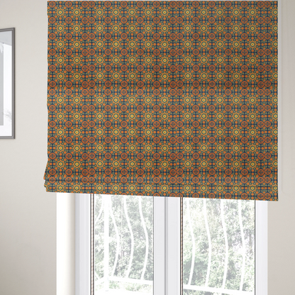 The fabric used to create these Roman blinds is a dense, symmetrical textile pattern featuring a repeating grid of pale yellow eight-pointed stars and orange circular medallions. The motifs are interconnected by delicate orange scrolling vines and tiny floral accents, set against a deep navy blue background. The colour palette consists of mustard yellow, burnt orange, and indigo.