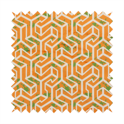 An orange and white textile fabric featuring a repeating, interlocking geometric pattern. The design consists of white outlines that form three-dimensional, maze-like structures or isometric blocks against a vibrant orange background. A textured, green moss-like speckled effect is scattered across the orange spaces, adding an organic contrast to the sharp, structured geometric lines.