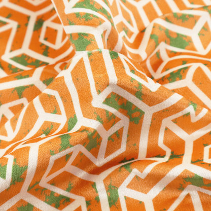 An orange and white textile fabric featuring a repeating, interlocking geometric pattern. The design consists of white outlines that form three-dimensional, maze-like structures or isometric blocks against a vibrant orange background. A textured, green moss-like speckled effect is scattered across the orange spaces, adding an organic contrast to the sharp, structured geometric lines.