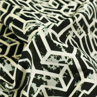 A black and off-white textile fabric featuring a repeating, interlocking geometric pattern. The design consists of off-white outlines that form three-dimensional, isometric maze-like structures against a solid black background. Distressed, pale green speckled textures are subtly integrated into the background spaces, giving the sharp, structured design a weathered, organic touch.