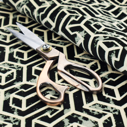 A black and off-white textile fabric featuring a repeating, interlocking geometric pattern. The design consists of off-white outlines that form three-dimensional, isometric maze-like structures against a solid black background. Distressed, pale green speckled textures are subtly integrated into the background spaces, giving the sharp, structured design a weathered, organic touch.