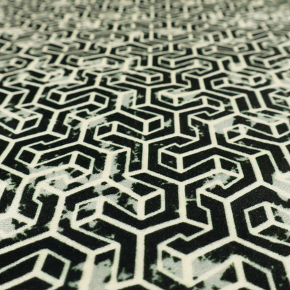 A black and off-white textile fabric featuring a small-scale, densely repeating interlocking geometric pattern. Fine off-white outlines construct complex, three-dimensional isometric block formations against a solid black background. Pale green, distressed textured speckles are integrated throughout, creating a weathered, organic contrast to the sharp geometric structure.