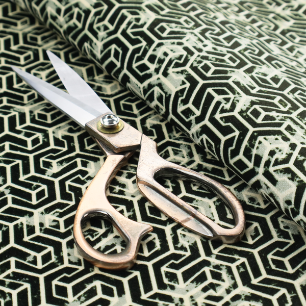 A black and off-white textile fabric featuring a small-scale, densely repeating interlocking geometric pattern. Fine off-white outlines construct complex, three-dimensional isometric block formations against a solid black background. Pale green, distressed textured speckles are integrated throughout, creating a weathered, organic contrast to the sharp geometric structure.
