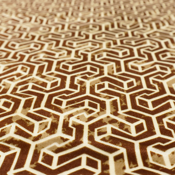 A brown and cream textile fabric featuring a small-scale, densely repeating interlocking geometric pattern. Fine cream-coloured outlines construct complex, three-dimensional isometric block formations against a warm, dark brown background. Lightly distressed, tan-speckled textures are integrated throughout, creating a weathered, organic contrast to the sharp geometric structure.