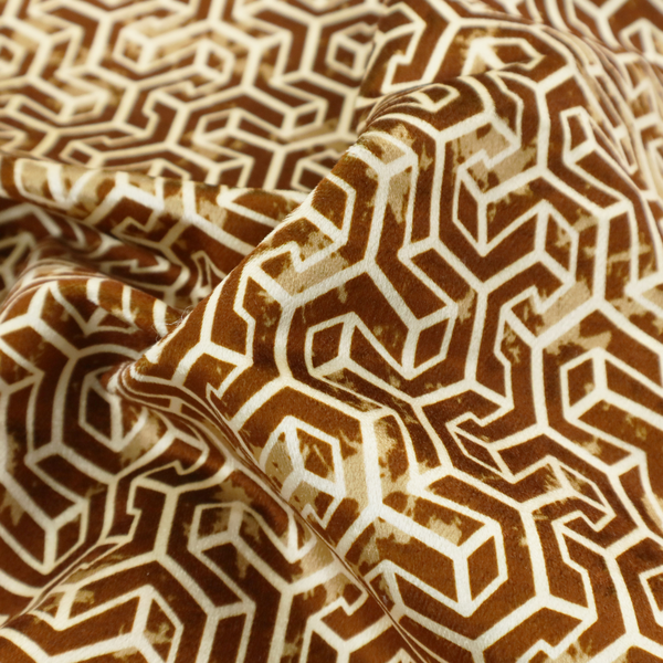 A brown and cream textile fabric featuring a small-scale, densely repeating interlocking geometric pattern. Fine cream-coloured outlines construct complex, three-dimensional isometric block formations against a warm, dark brown background. Lightly distressed, tan-speckled textures are integrated throughout, creating a weathered, organic contrast to the sharp geometric structure.