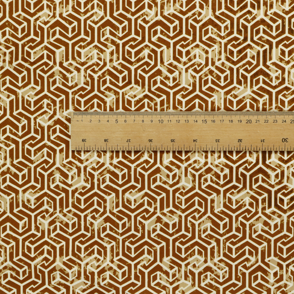 A brown and cream textile fabric featuring a small-scale, densely repeating interlocking geometric pattern. Fine cream-coloured outlines construct complex, three-dimensional isometric block formations against a warm, dark brown background. Lightly distressed, tan-speckled textures are integrated throughout, creating a weathered, organic contrast to the sharp geometric structure.