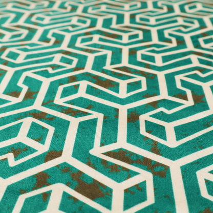 A teal and off-white textile fabric featuring a repeating, interlocking geometric pattern. The design consists of off-white outlines forming three-dimensional, isometric maze-like structures against a deep teal background. Distressed, brown speckled textures are subtly scattered throughout the teal spaces, giving the structured, geometric layout a weathered, organic touch.