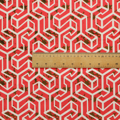 A red and off-white textile fabric featuring a repeating, interlocking geometric pattern. The design consists of off-white outlines forming three-dimensional, isometric maze-like structures against a vibrant coral red background. Distressed, dark brown speckled textures are subtly scattered throughout the red spaces, adding a weathered, organic touch to the structured, geometric design.