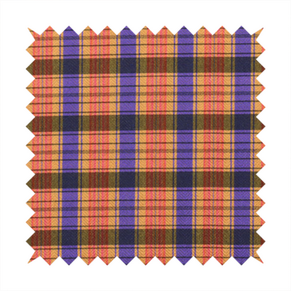 A vibrant, multi-coloured plaid fabric featuring a complex grid of horizontal and vertical stripes. The pattern blends deep indigo, golden ochre, and olive green, highlighted by thin, high-contrast stripes of bright violet and coral pink.