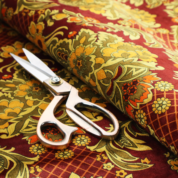 An ornate damask fabric featuring large, symmetrical floral medallions in shades of sage green, golden ochre, and muted orange.