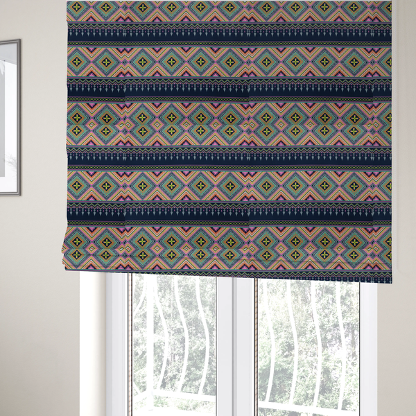 The fabric used to create these Roman blinds is a vibrant, repeating geometric Aztec or tribal fabric pattern organized in horizontal bands. The design features alternating wide stripes of colourful diamond and zigzag motifs against narrower dark navy bands filled with intricate chevron and tassel-like embroidery accents.