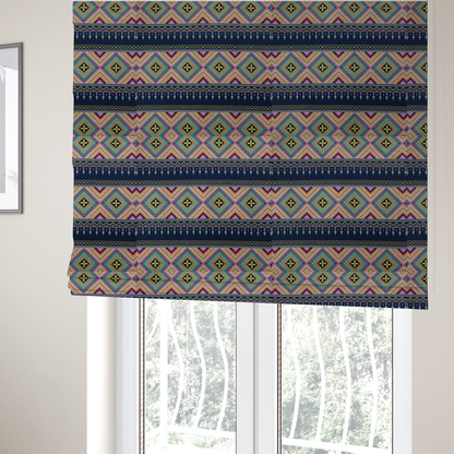 The fabric used to create these Roman blinds is a vibrant, repeating geometric Aztec or tribal fabric pattern organized in horizontal bands. The design features alternating wide stripes of colourful diamond and zigzag motifs against narrower dark navy bands filled with intricate chevron and tassel-like embroidery accents.