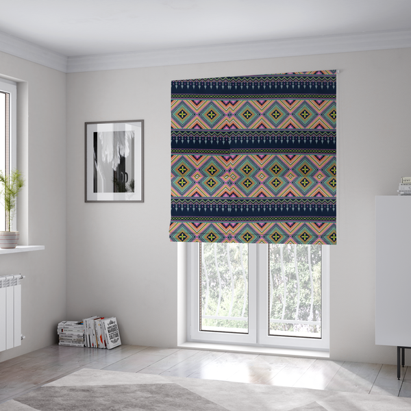 The fabric used to create these Roman blinds is a vibrant, repeating geometric Aztec or tribal fabric pattern organized in horizontal bands. The design features alternating wide stripes of colourful diamond and zigzag motifs against narrower dark navy bands filled with intricate chevron and tassel-like embroidery accents.