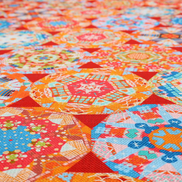 A vibrant, kaleidoscope-inspired fabric pattern composed of interlocking circular and octagonal medallions set against a rich, fiery red-orange background.