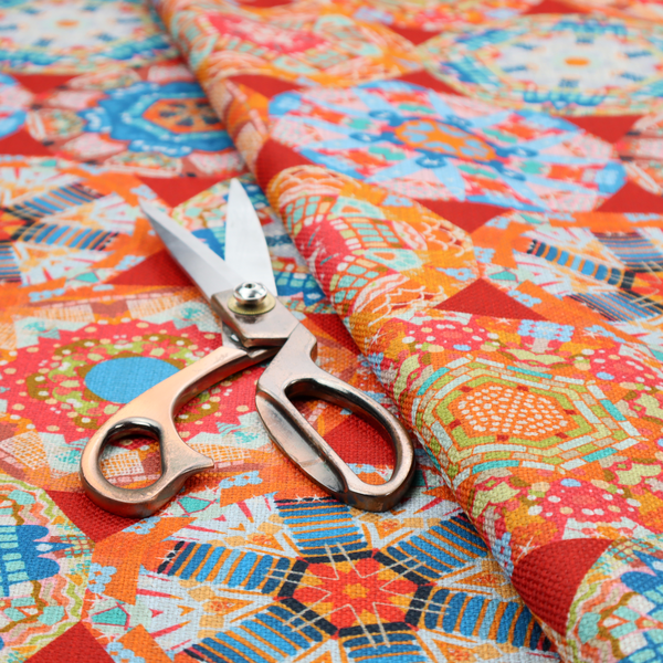 A vibrant, kaleidoscope-inspired fabric pattern composed of interlocking circular and octagonal medallions set against a rich, fiery red-orange background.