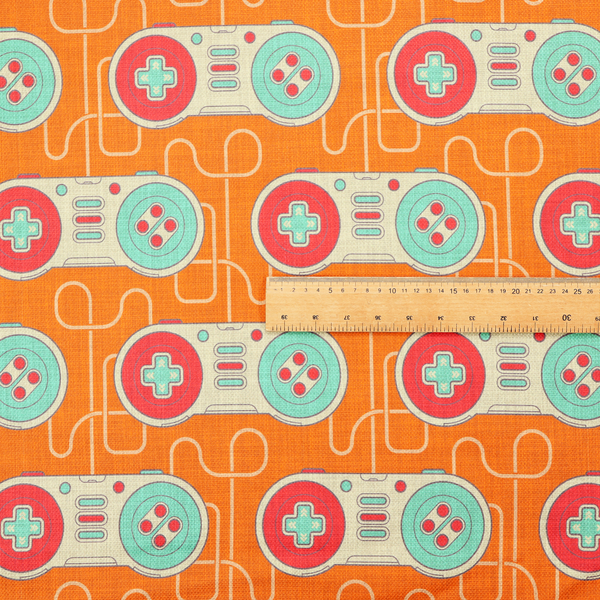 A playful, retro-inspired repeating fabric pattern featuring classic video game controllers connected by winding cord lines set against a warm orange background.