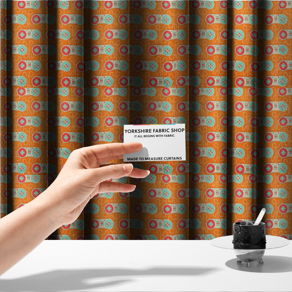 The fabric used to create these made-to-measure curtains is a playful, retro-inspired repeating fabric pattern featuring classic video game controllers connected by winding cord lines set against a warm orange background.
