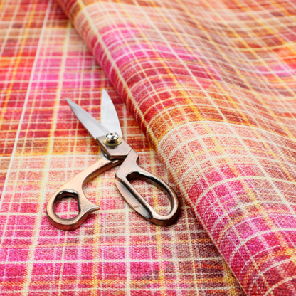 This fabric features an intricate, layered plaid pattern that blends warm tones of red, orange, yellow, and deep pink. The design has a slightly blurred, watercolour effect with a dense grid of fine white and gold lines overlapping the vibrant colours.