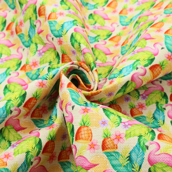 This fabric features a tropical pattern on a light, neutral background, densely decorated with illustrations of bright pink flamingos, pineapples, lush green tropical leaves, and small purple and pink flowers.