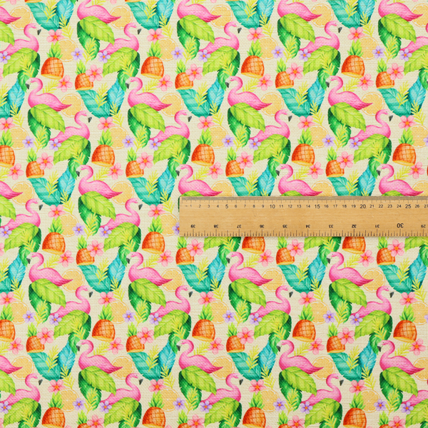 This fabric features a tropical pattern on a light, neutral background, densely decorated with illustrations of bright pink flamingos, pineapples, lush green tropical leaves, and small purple and pink flowers.