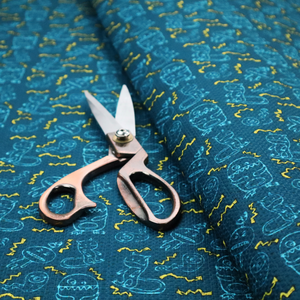 This fabric features a playful, dark teal background covered in a whimsical pattern of small, light blue line-art monsters and yellow zigzagging lightning bolt accents.