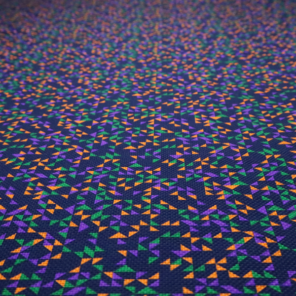 This fabric features a dense geometric pattern of tiny, randomly oriented triangles in shades of purple, green, and orange scattered across a solid dark navy blue background.