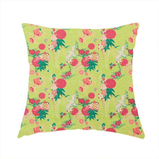 The fabric used to create this handmade cushion is a fabric features a whimsical, Chinoiseries-inspired pattern on a bright chartreuse-green background, repeating illustrations of white cranes, large dark pink pom-pom flowers, and leafy green ferns.