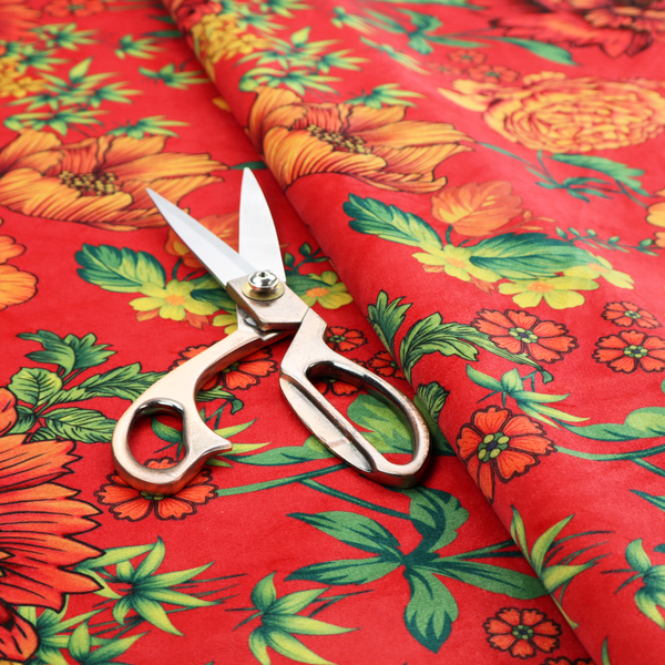 A vibrant red fabric featuring a repeating Chinoiseries floral pattern with large, detailed peony and marigold blossoms in shades of orange and yellow, accented by green leaves and stems.