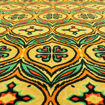 Fabric print featuring a repeating retro ikat ogee pattern. The geometric design displays a lattice of mustard yellow onion arches, green leaf shapes, and four-leaf clover medallions outlined in fuzzy black brushstrokes with pops of coral orange.