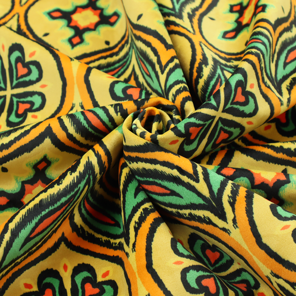Fabric print featuring a repeating retro ikat ogee pattern. The geometric design displays a lattice of mustard yellow onion arches, green leaf shapes, and four-leaf clover medallions outlined in fuzzy black brushstrokes with pops of coral orange.
